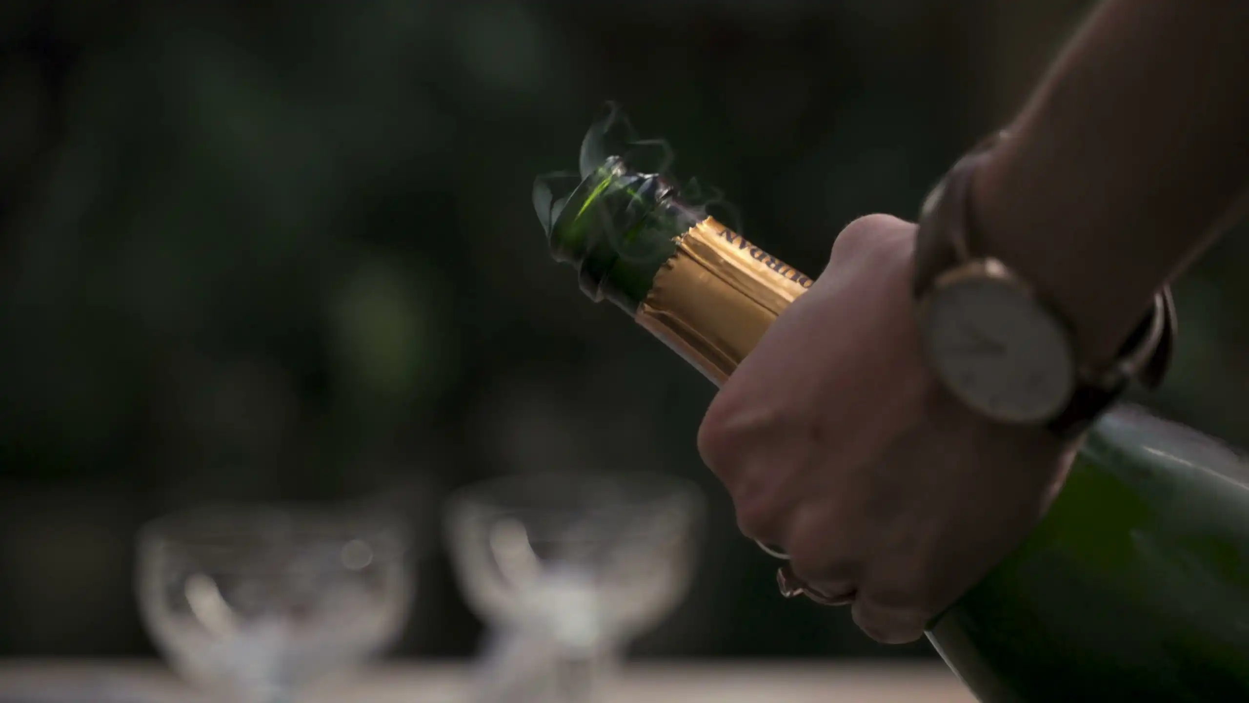A hand easing the cork from a sparkling bottle