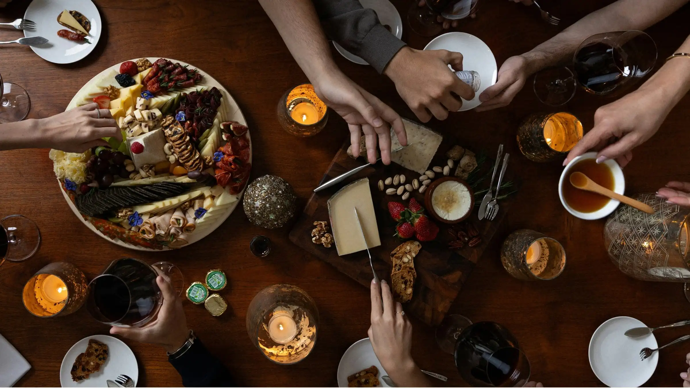 A spread of cheeses on a dark table seen from above