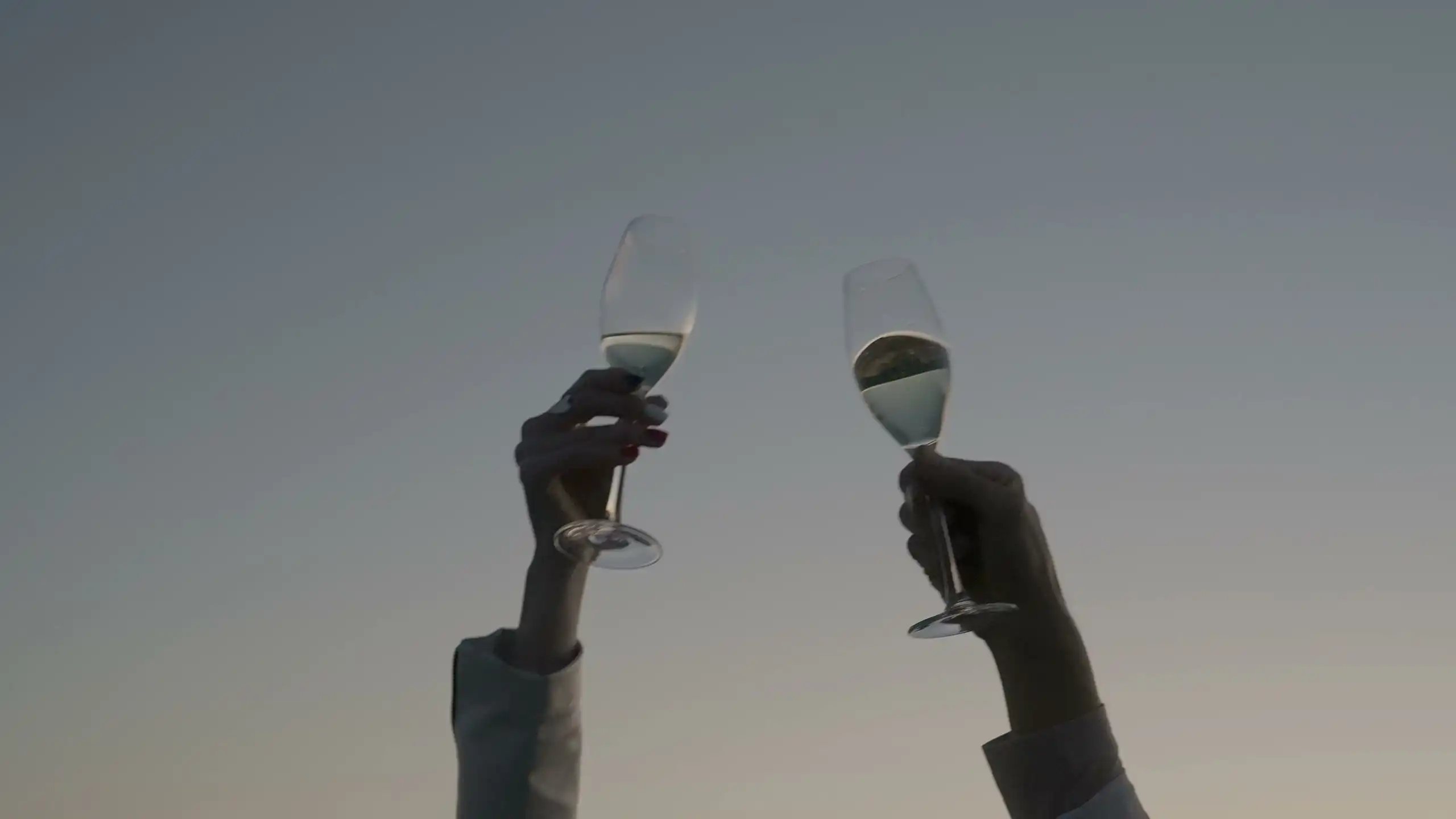 Glasses of sparkling wine raised together at dusk