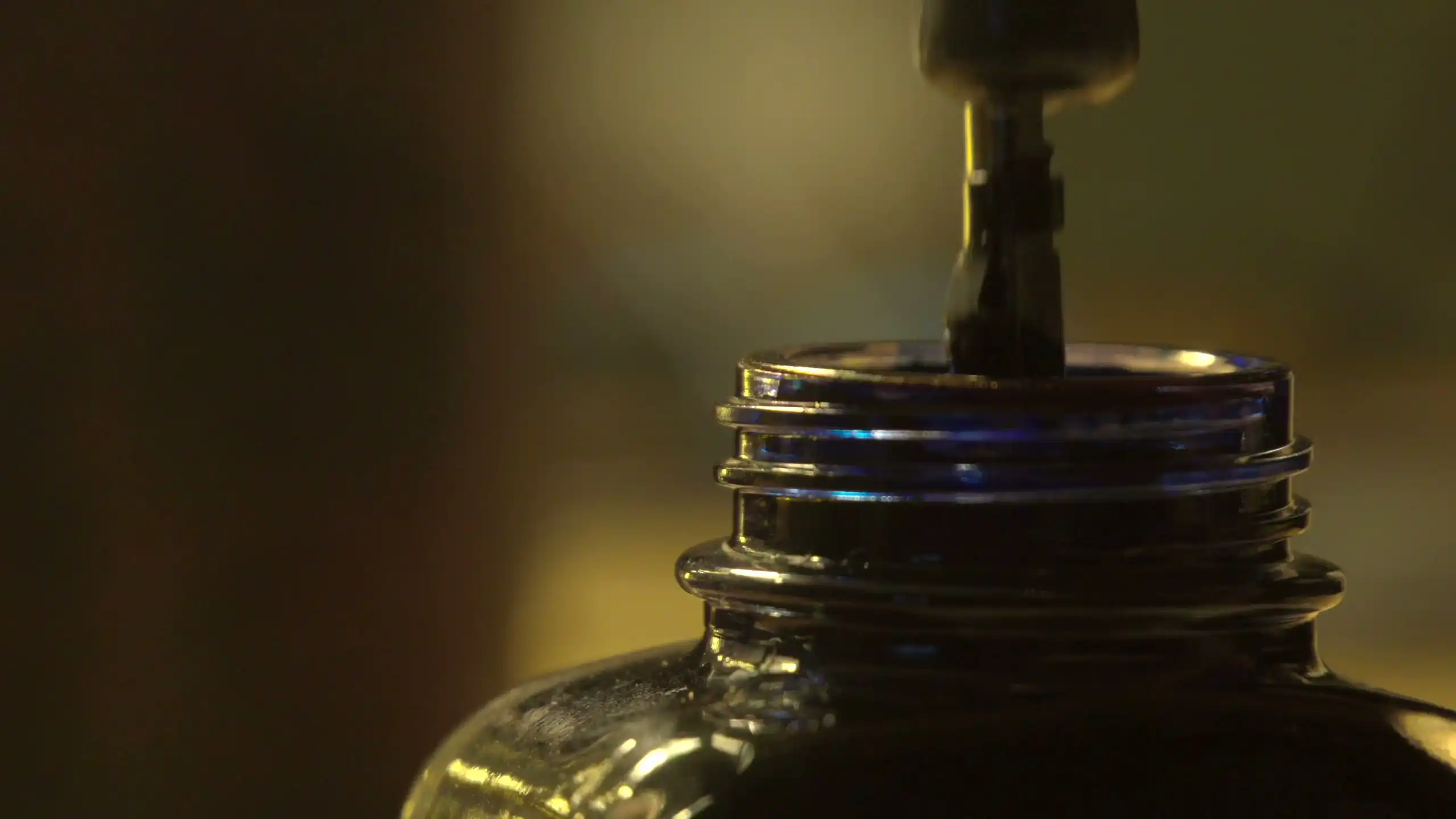 A pen dipping into a bottle of dark ink