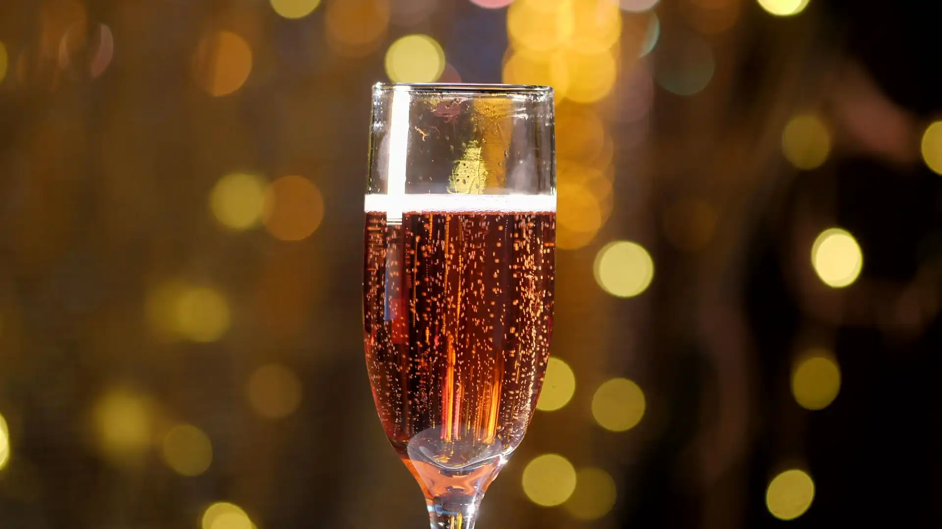 Pale pink sparkling wine poured into a glass, bubbles catching the light